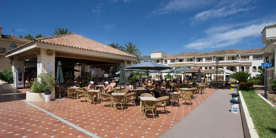 Außenterrasse im Hotel Puente Real, Torremolinos: Tische, Stühle und Sonnenschirme.