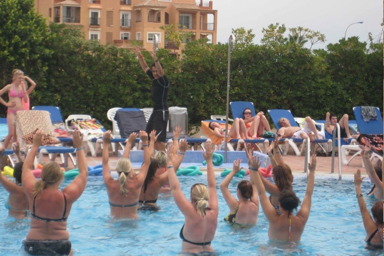 un groupe de femmes se tient dans une piscine avec leurs bras en l' air