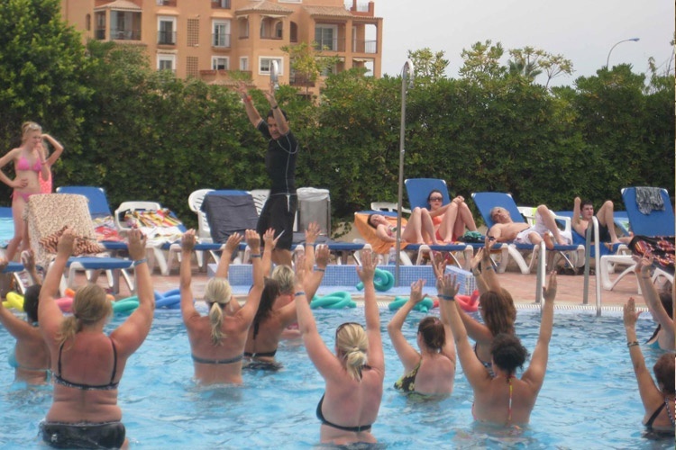 eine Gruppe von Frauen steht in einem Pool und hebt ihre Hände in die Luft