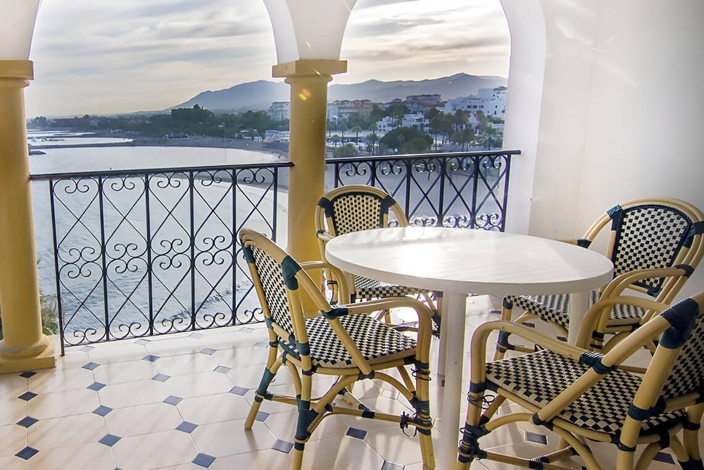 a balcony with a table and chairs overlooking the ocean