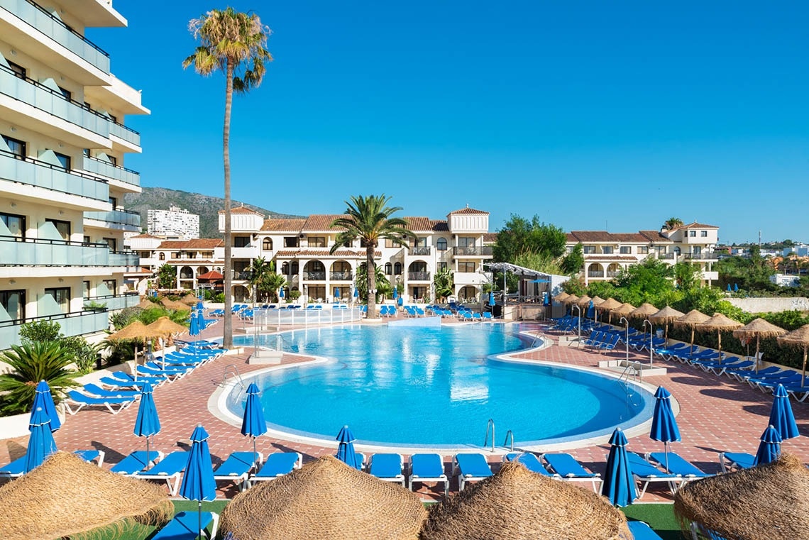 una gran piscina rodeada de sillas y sombrillas en un resort