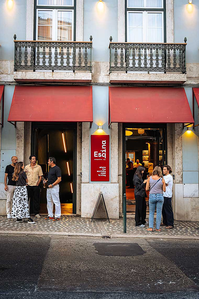 Exterior view of a hotel entrance with red awnings and a sign for "Esq. TEST3: Copia 4. Cosmopolitan Edge.