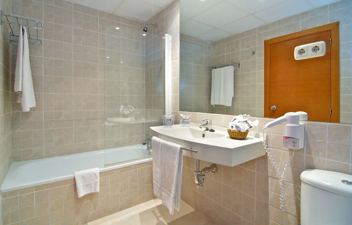 Modern bathroom at Hotel Puente Real Torremolinos with shower, sink, and hairdryer.