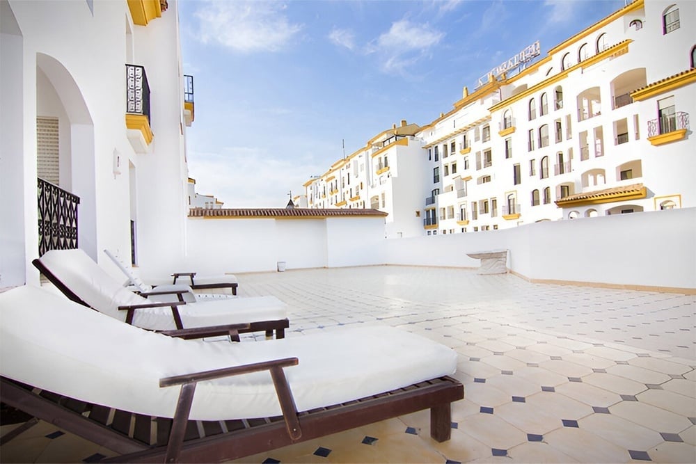 una terraza con sillas blancas y un edificio blanco en el fondo