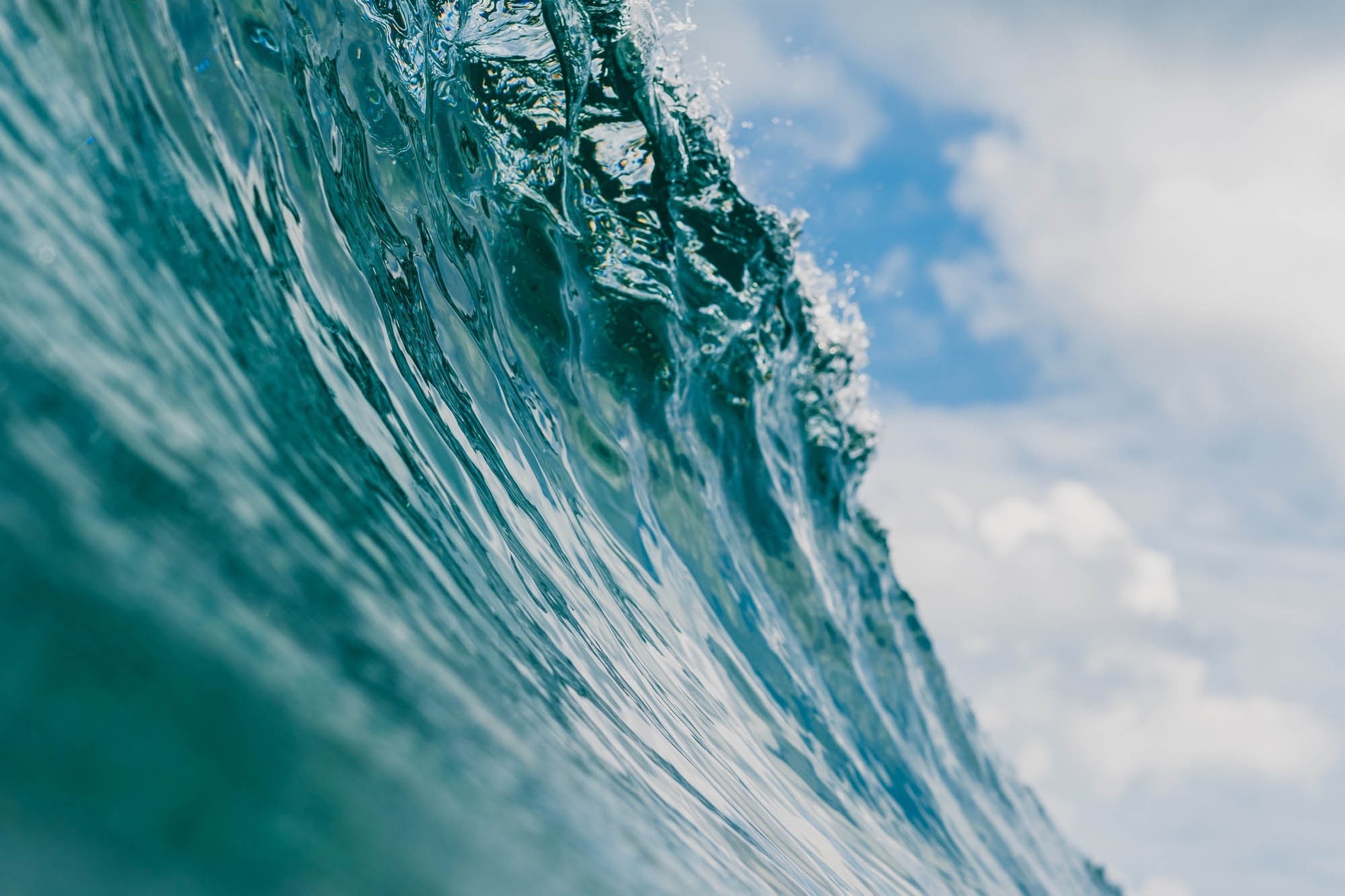 a wave in the ocean with a blue sky in the background