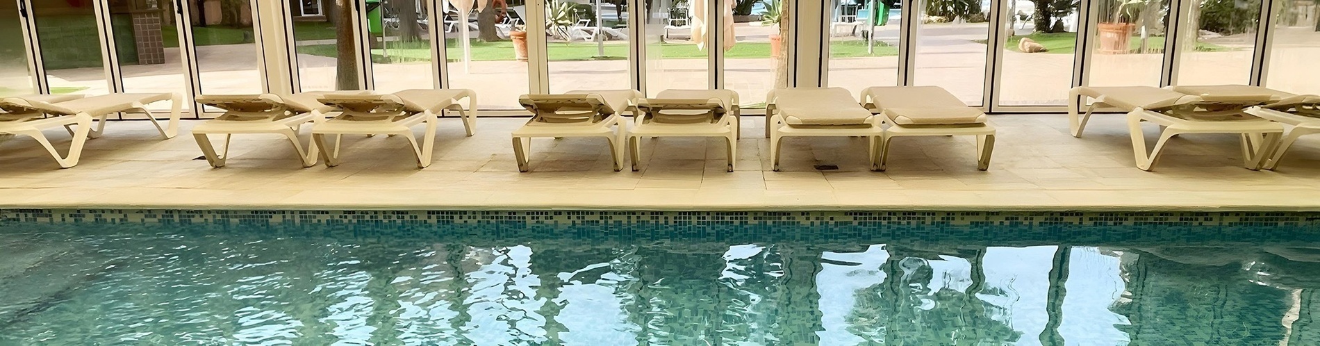 una fila de sillas de playa junto a una piscina