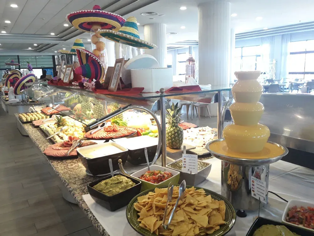 Mexikanisches Themen-Frühstücksbuffet im Hotel Puente Real ****, Torremolinos, mit bunten Hüten und gesunden Optionen.