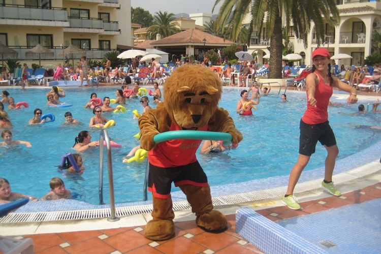 a mascot in a lion costume stands in front of a swimming pool