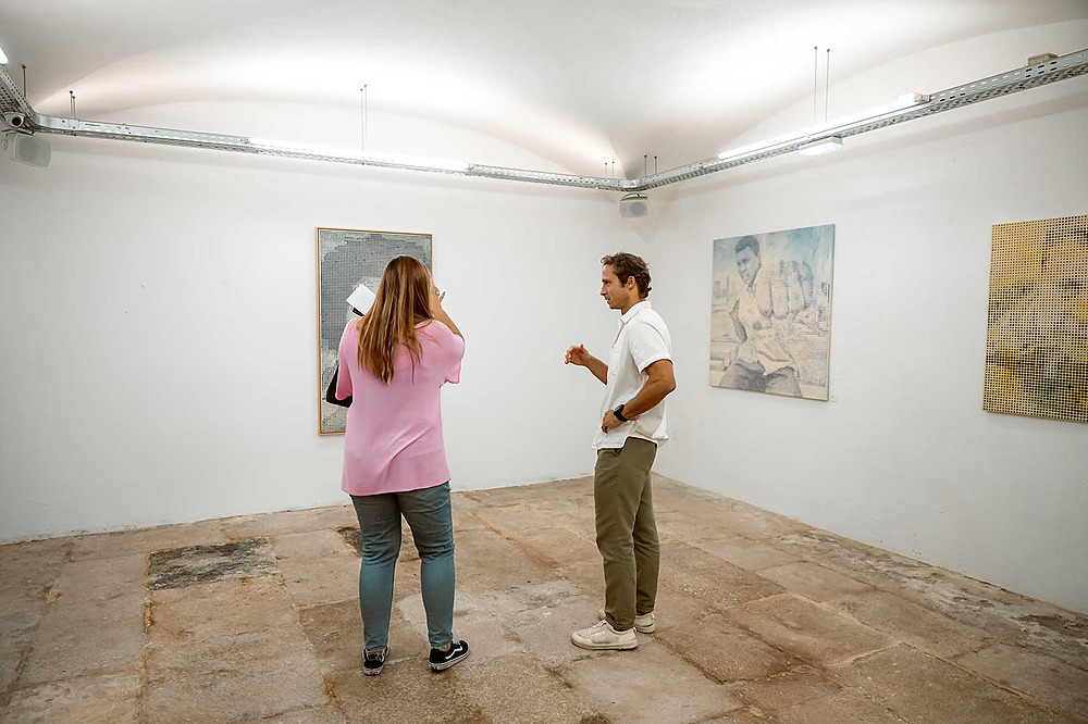 Art exhibition TEST3: Copia 4: a man and woman discuss paintings in a modern gallery.
