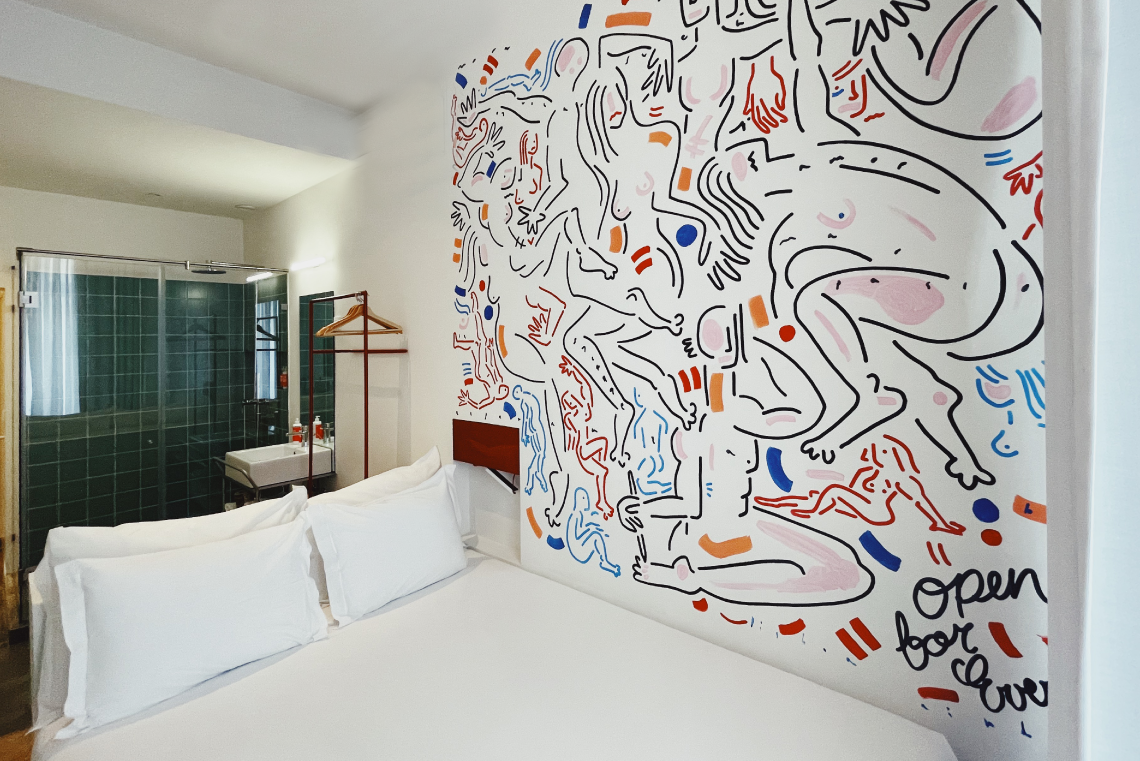 TEST3: Copia 4: Quarto de hotel moderno com mural artístico, cama branca e banheiro privativo.