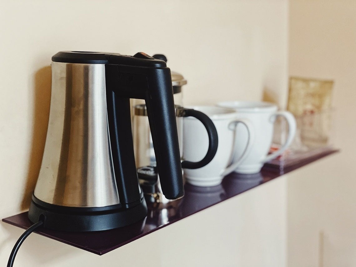 TEST3: Copia 4: Cafeteira e xícaras brancas em prateleira de hotel para seu café da manhã.