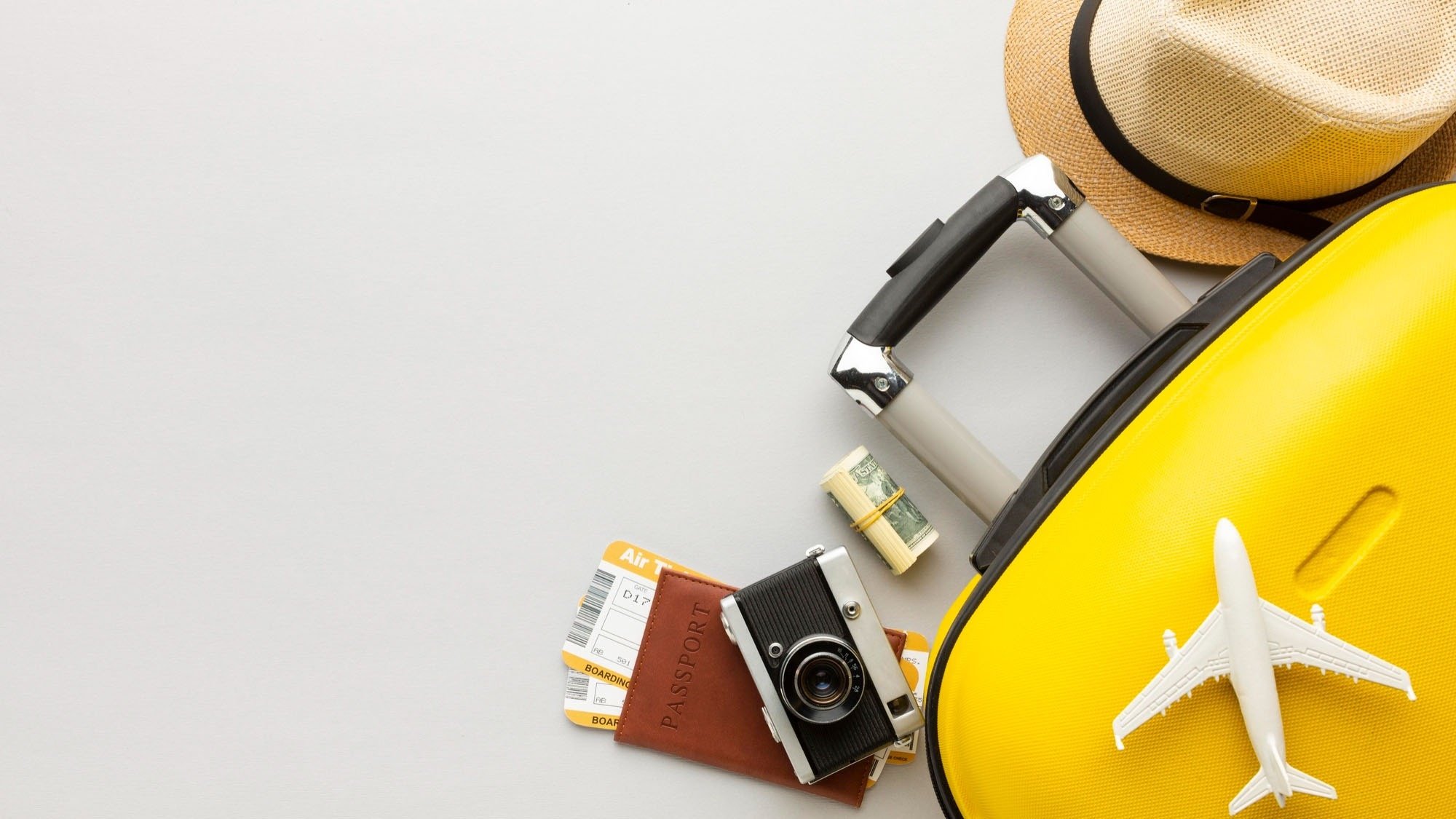 a yellow suitcase with a passport camera tickets and a hat