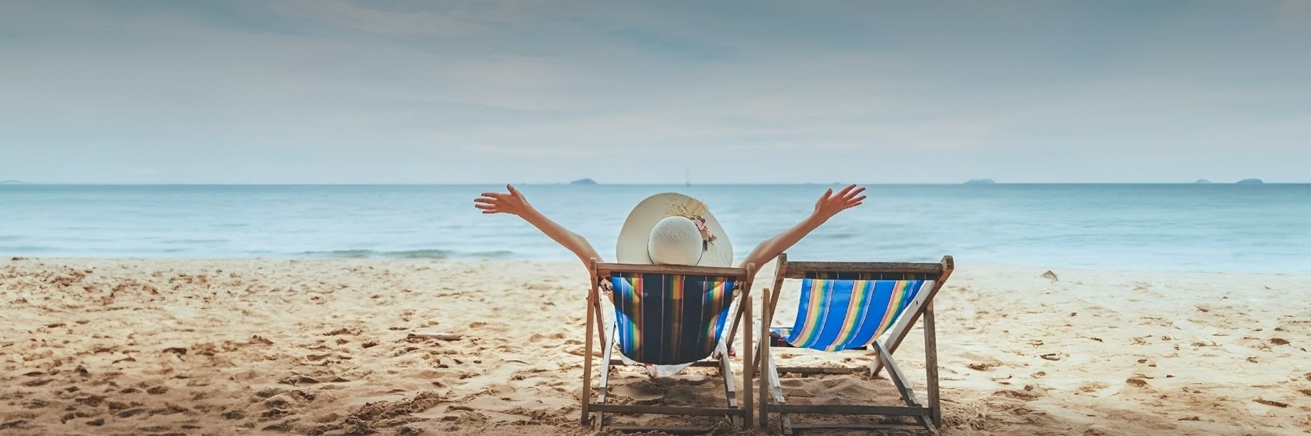 una mujer se sienta en una silla de playa con las manos en el aire