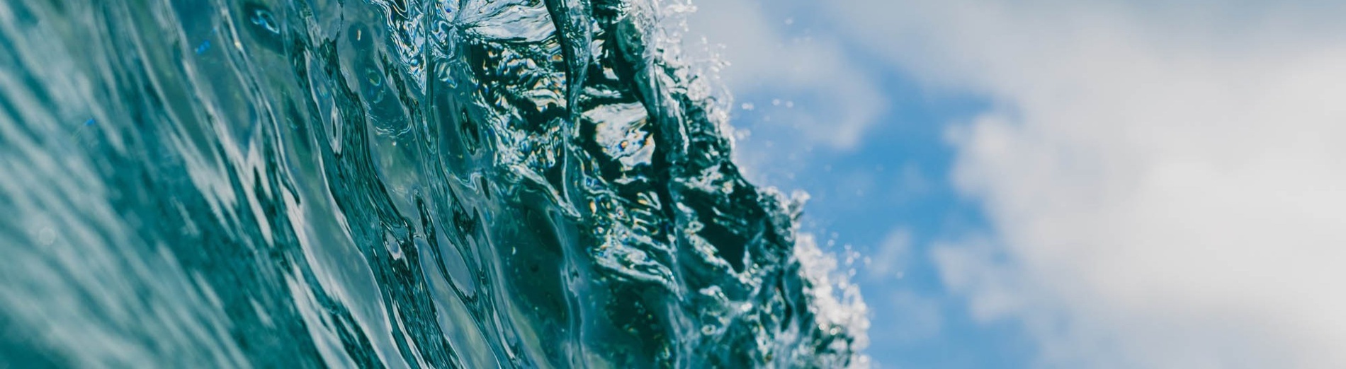 a wave in the ocean with a blue sky in the background