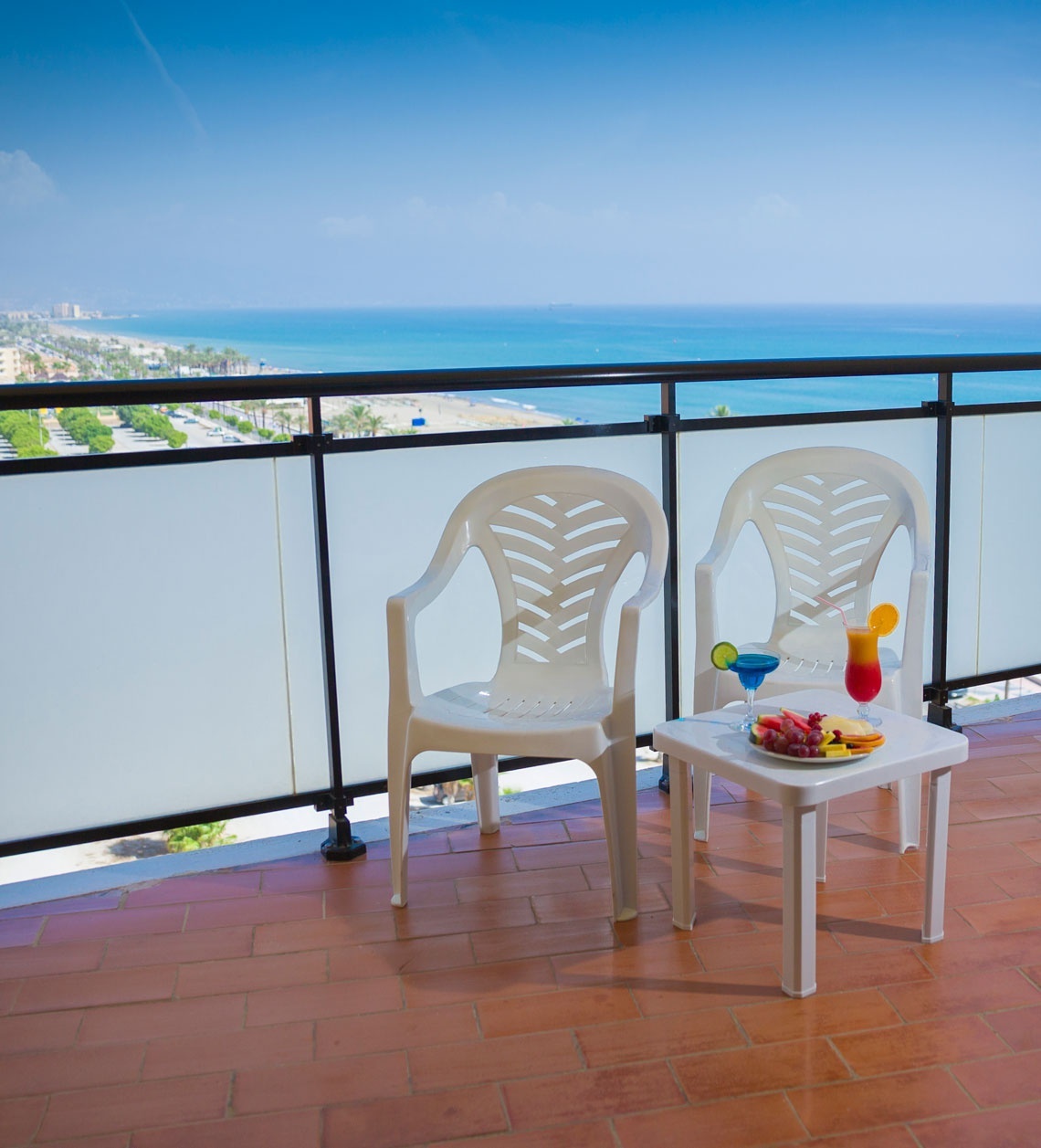 a balcony with two chairs and a table with a drink on it
