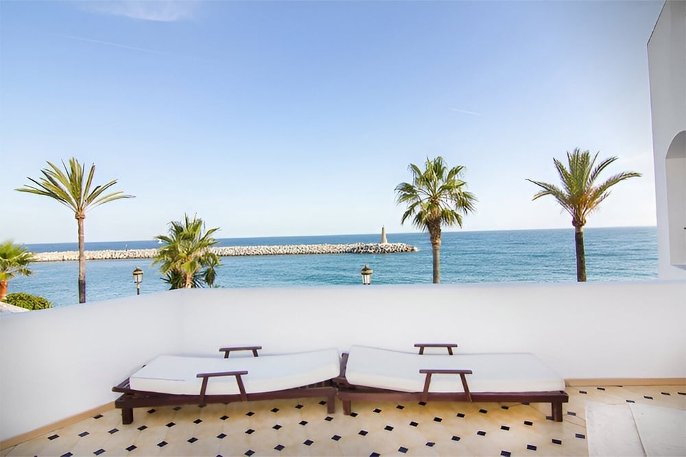 two lounge chairs on a balcony overlooking the ocean