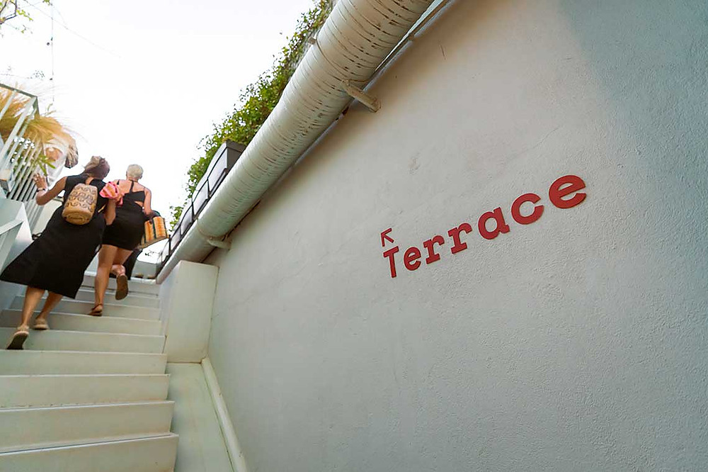 Two women ascend stairs toward TEST3: Copia 4 with a sign on the wall.