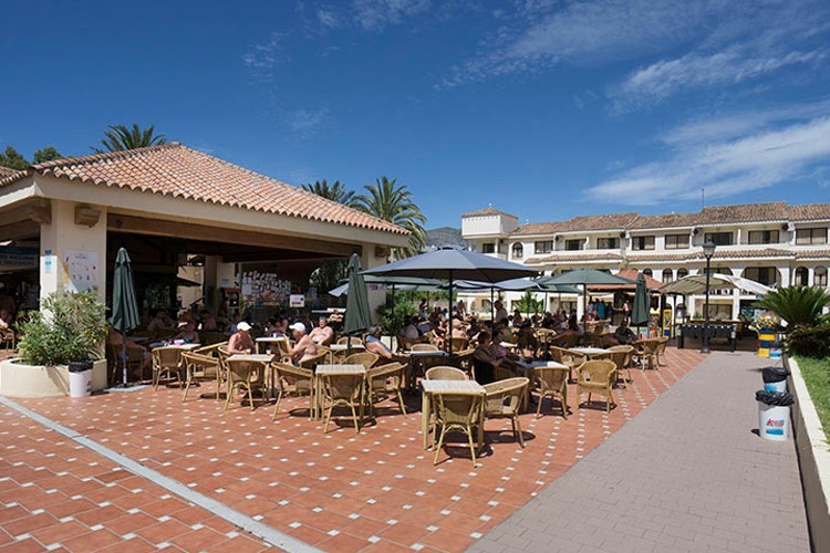 un groupe de personnes assises à des tables et des parasols à l' extérieur d' un restaurant