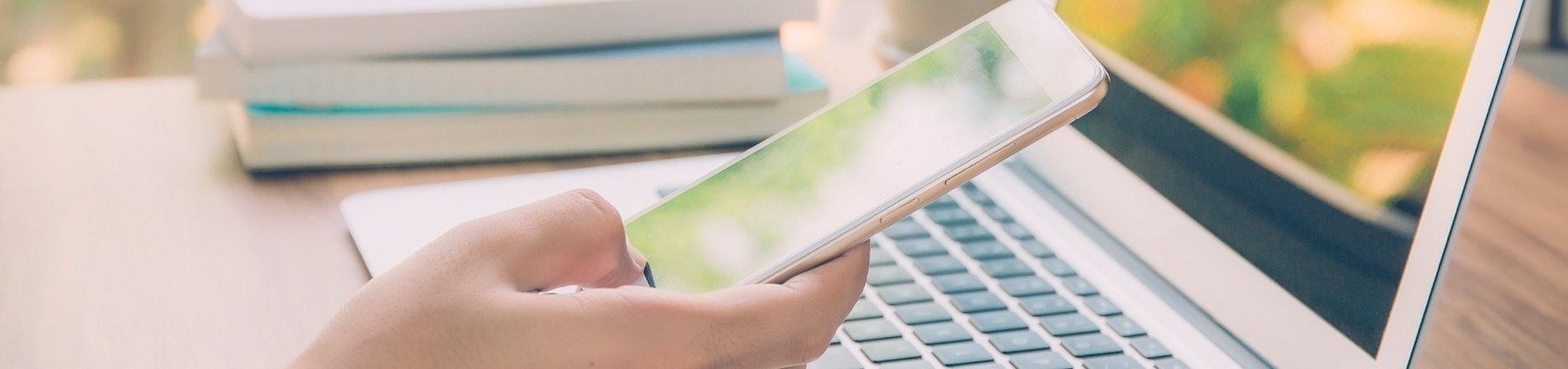 a person holding a cell phone in front of a laptop