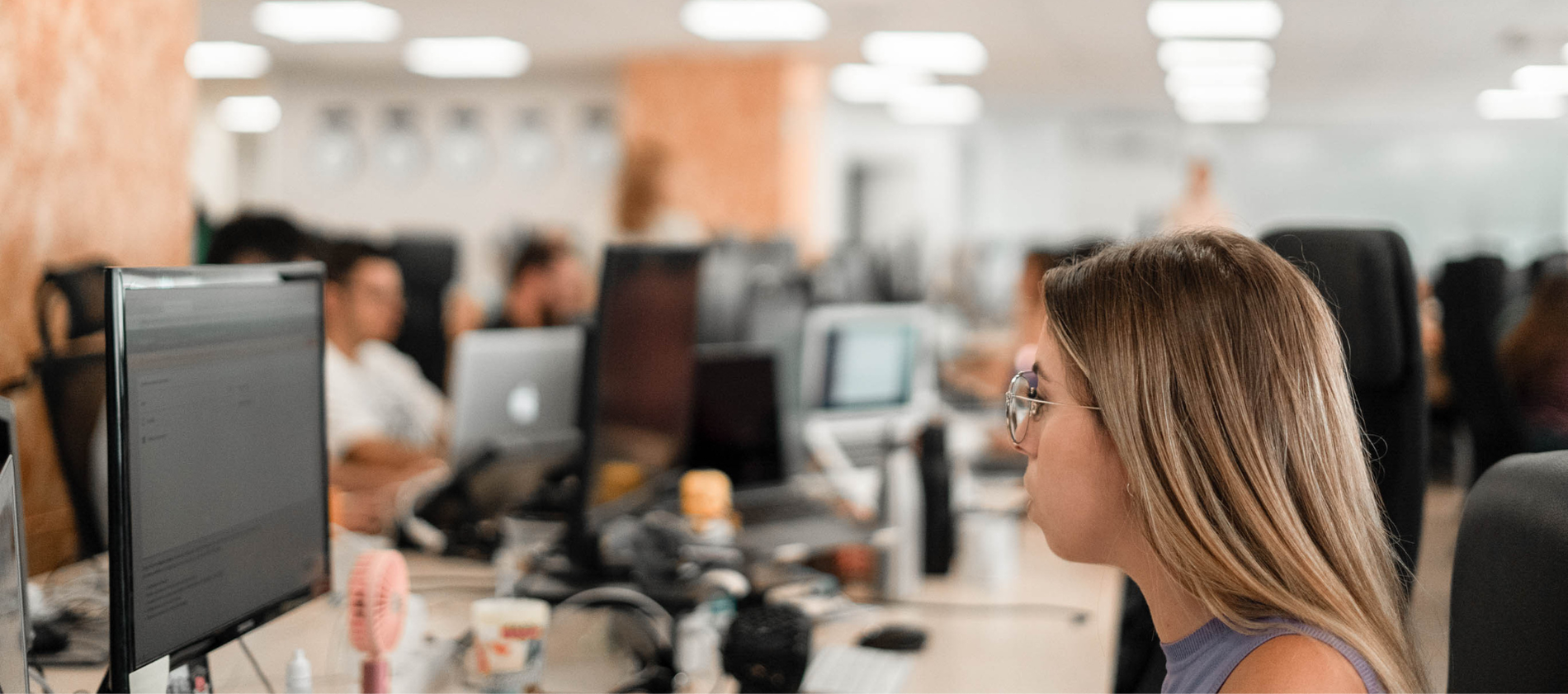 a woman wearing glasses looks at a computer screen