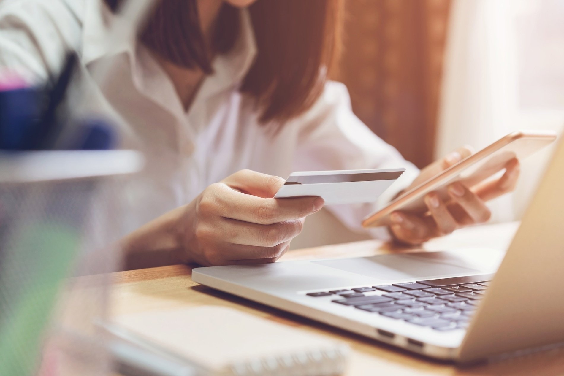 a woman is holding a credit card in front of a laptop