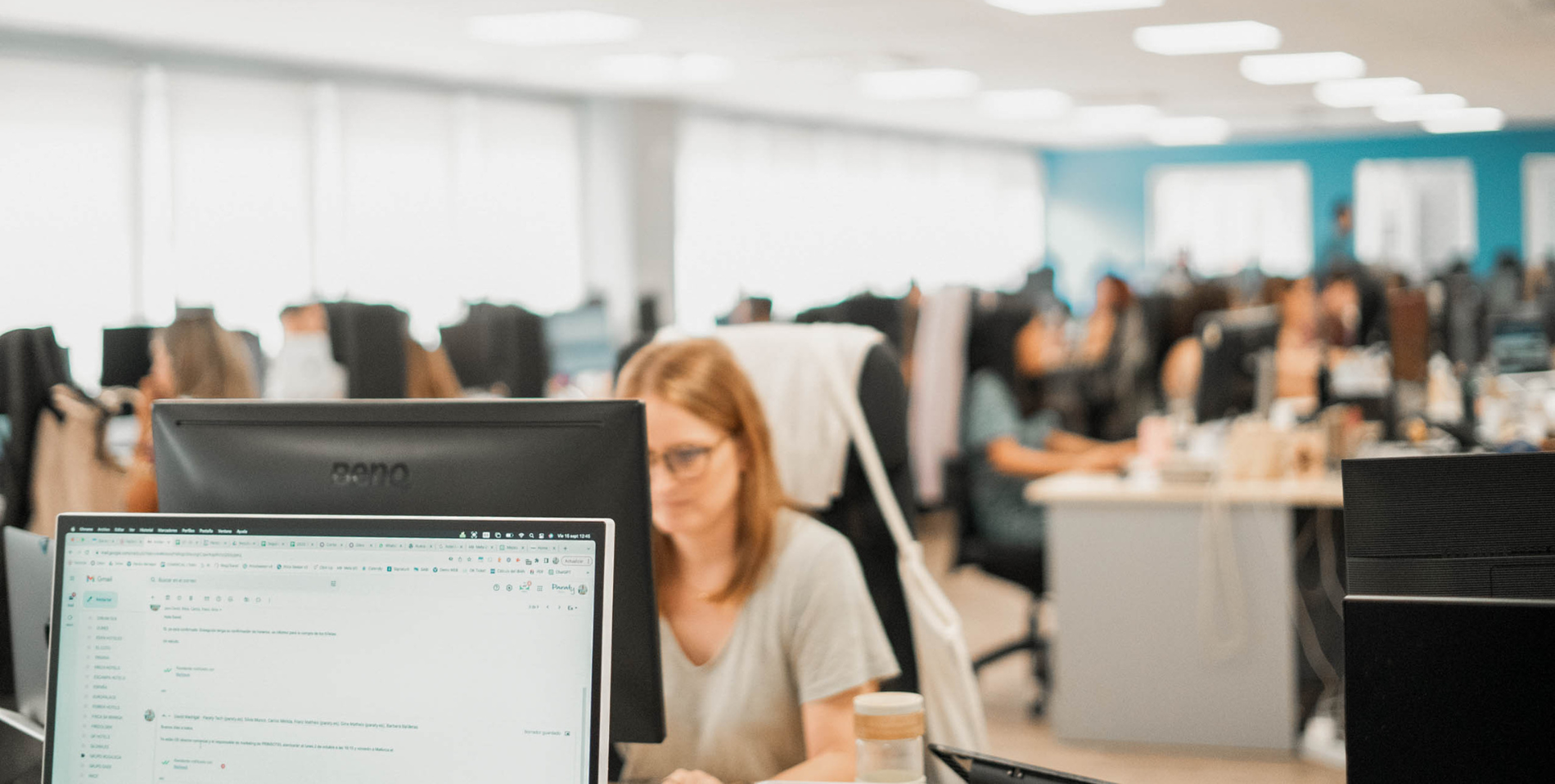 uma mulher está sentada em frente a um computador com uma mensagem no gmail na tela