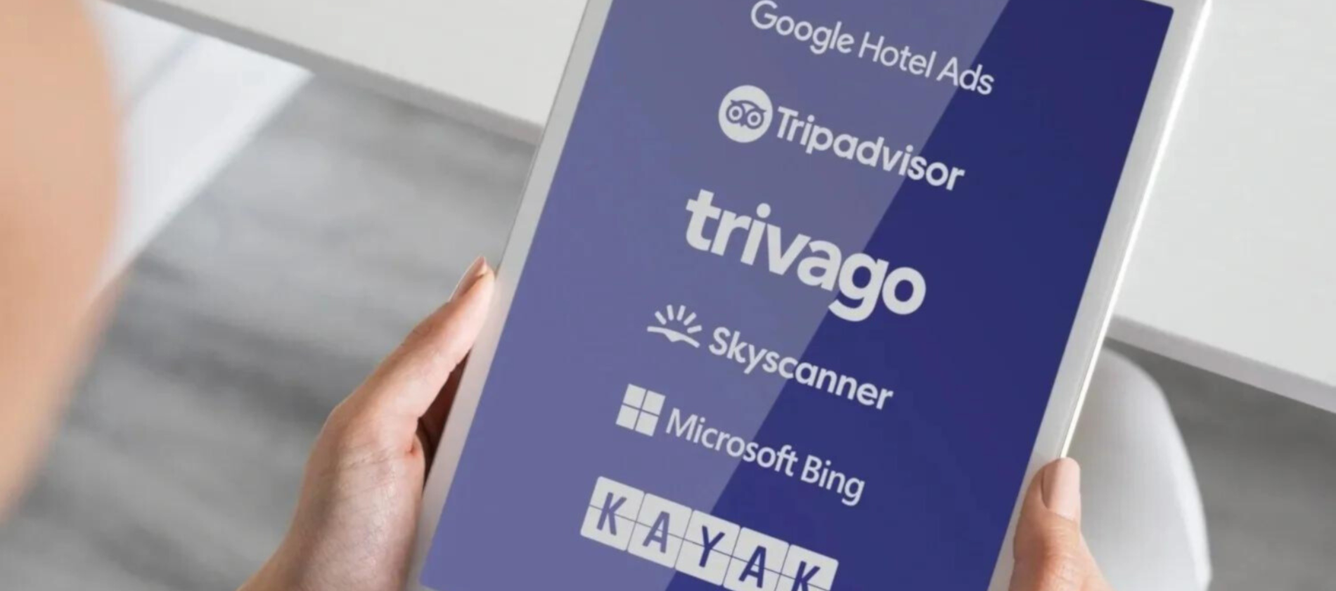 una persona sostiene una tableta con los logos de google hotel ads tripadvisor triviago skyscanner y microsoft bing
