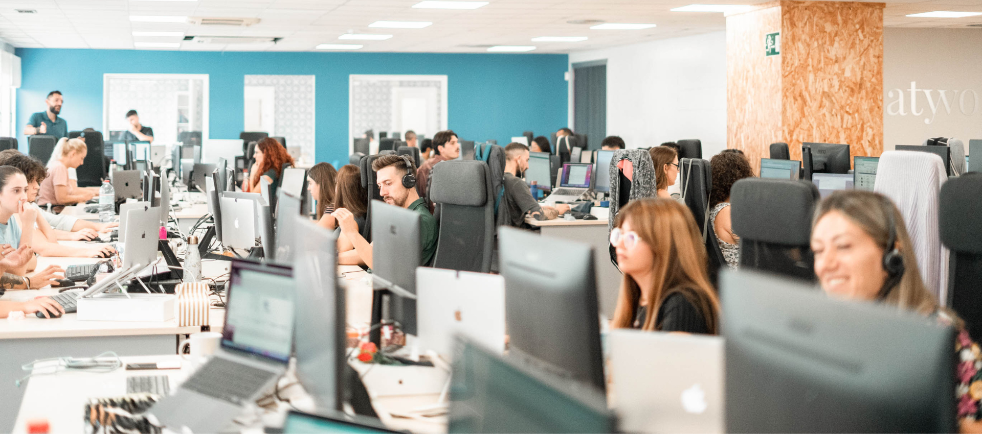 un grupo de hombres y mujeres están trabajando en una oficina llena de computadoras