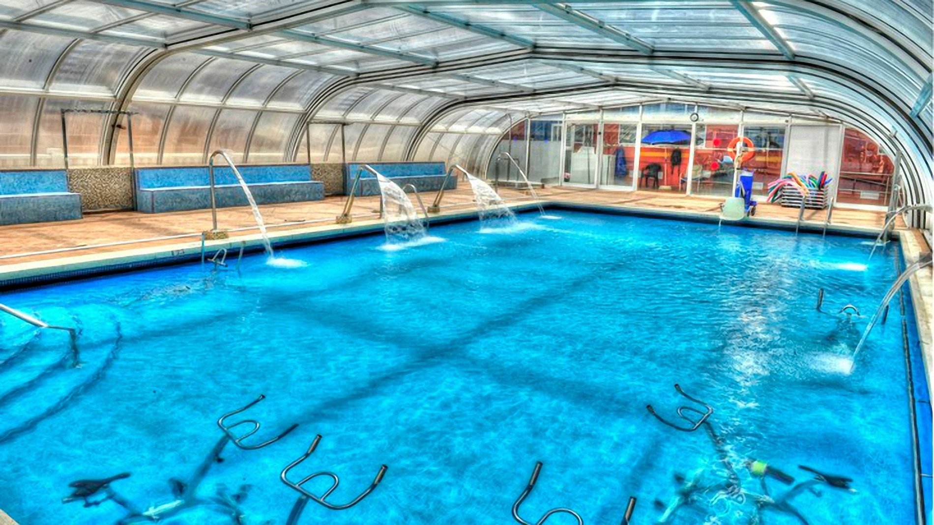 a large indoor swimming pool under a clear roof