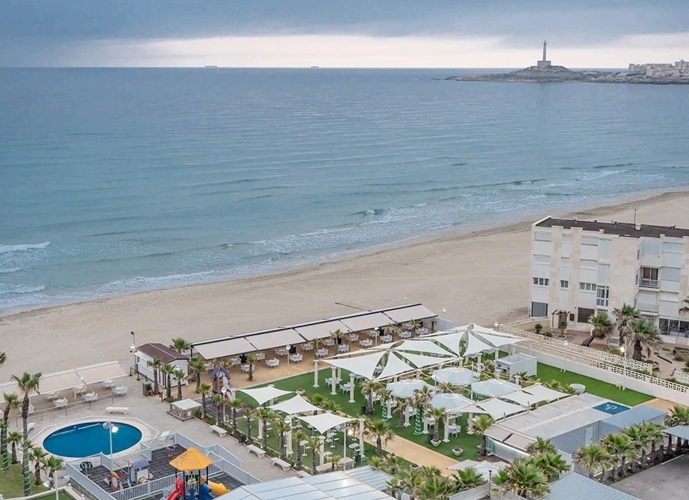 an aerial view of a beach with a building in the background