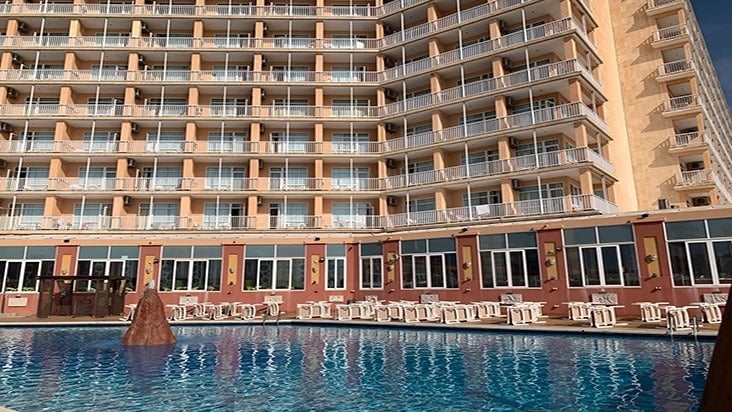 a swimming pool in front of a large Entremares hotel building