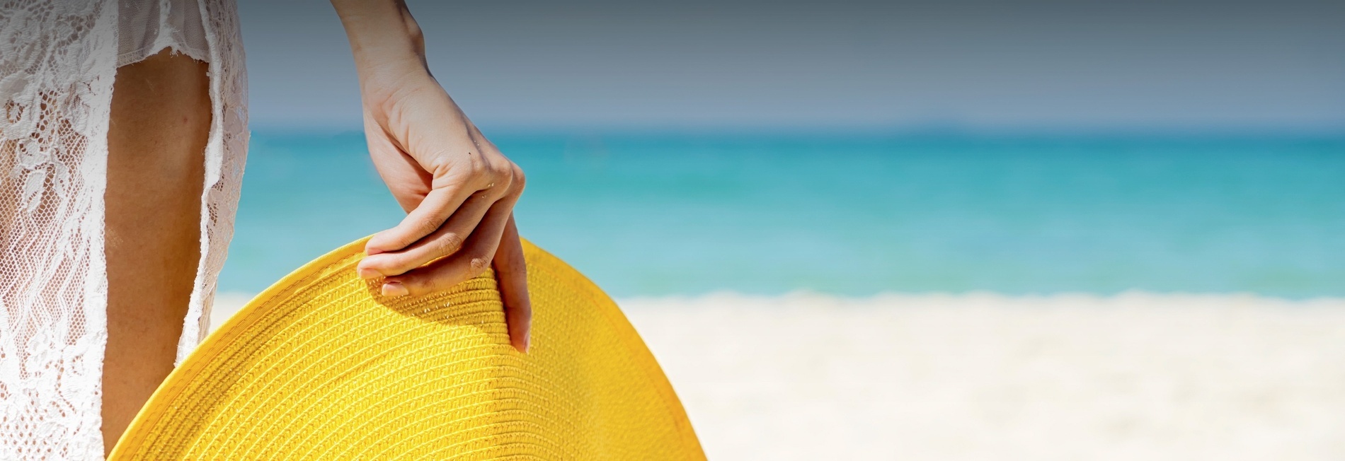 a woman sits under an orange umbrella on the beach