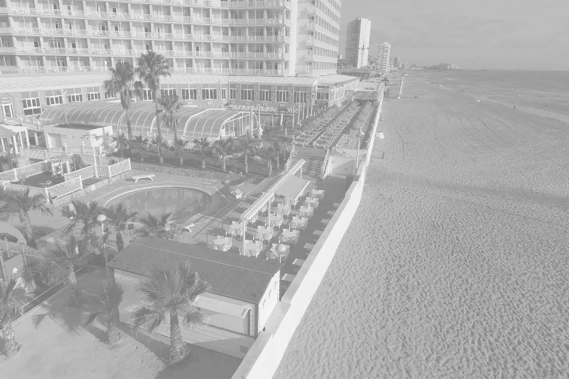 a black and white photo of a beach with a hotel in the background=s1900