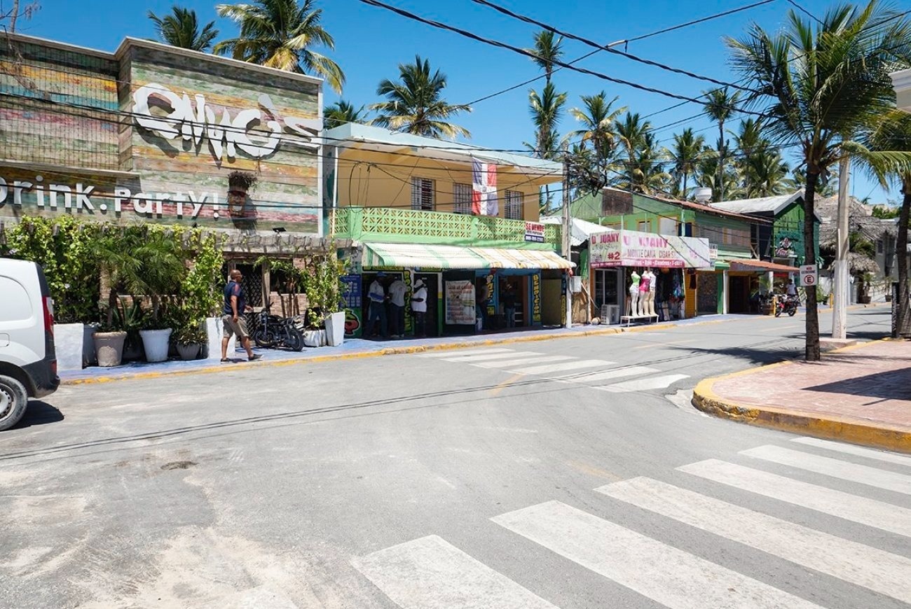 una mujer con un sombrero camina por un callejón con flores moradas