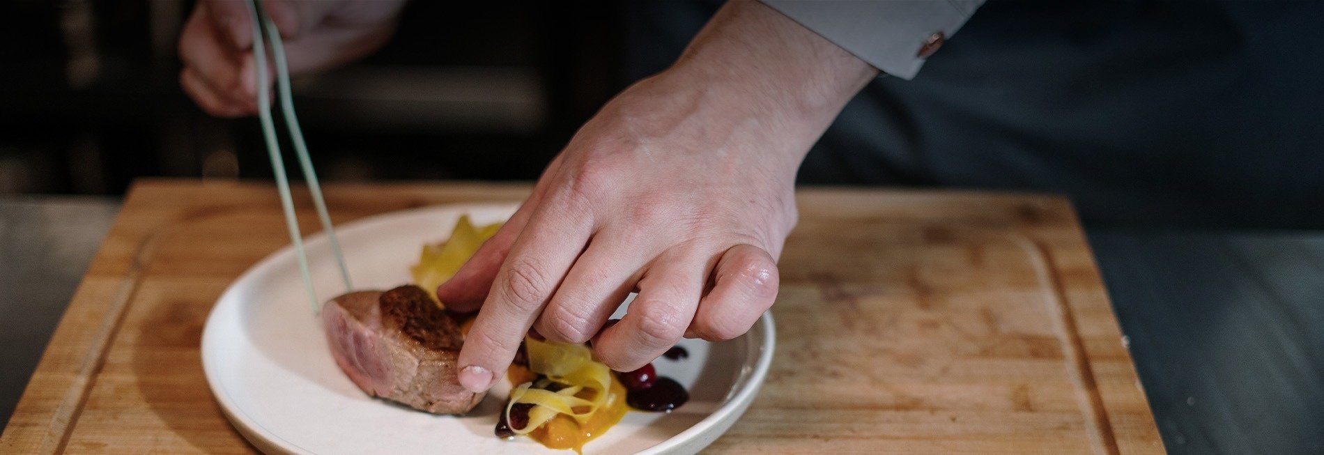 un chef prepara un plato de comida en una tabla de cortar de madera