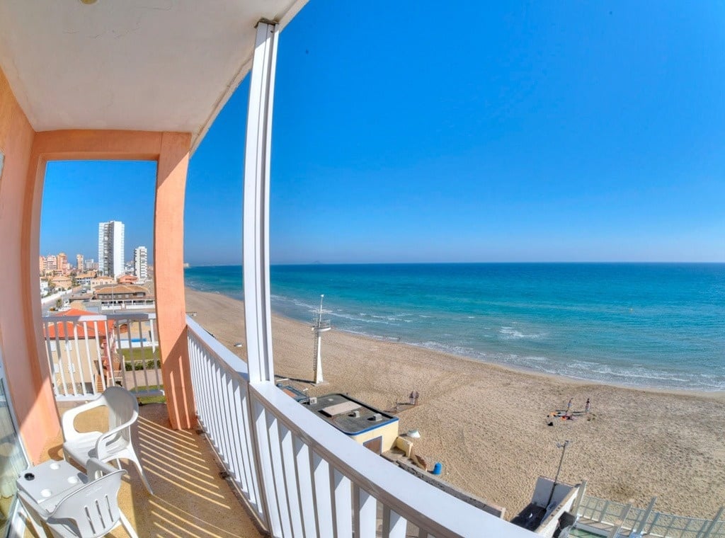 una vista de la playa desde un balcón con sillas y mesas
