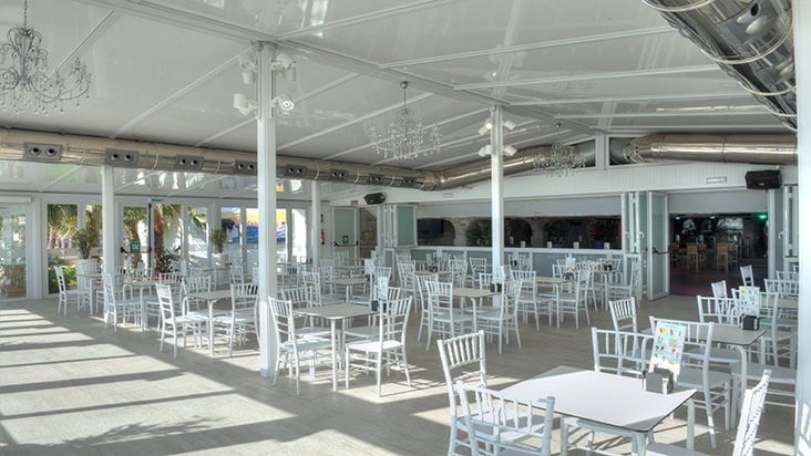 a restaurant with white tables and chairs and a chandelier