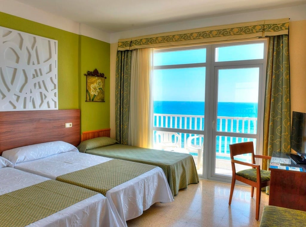 a hotel room with two beds and a balcony overlooking the ocean