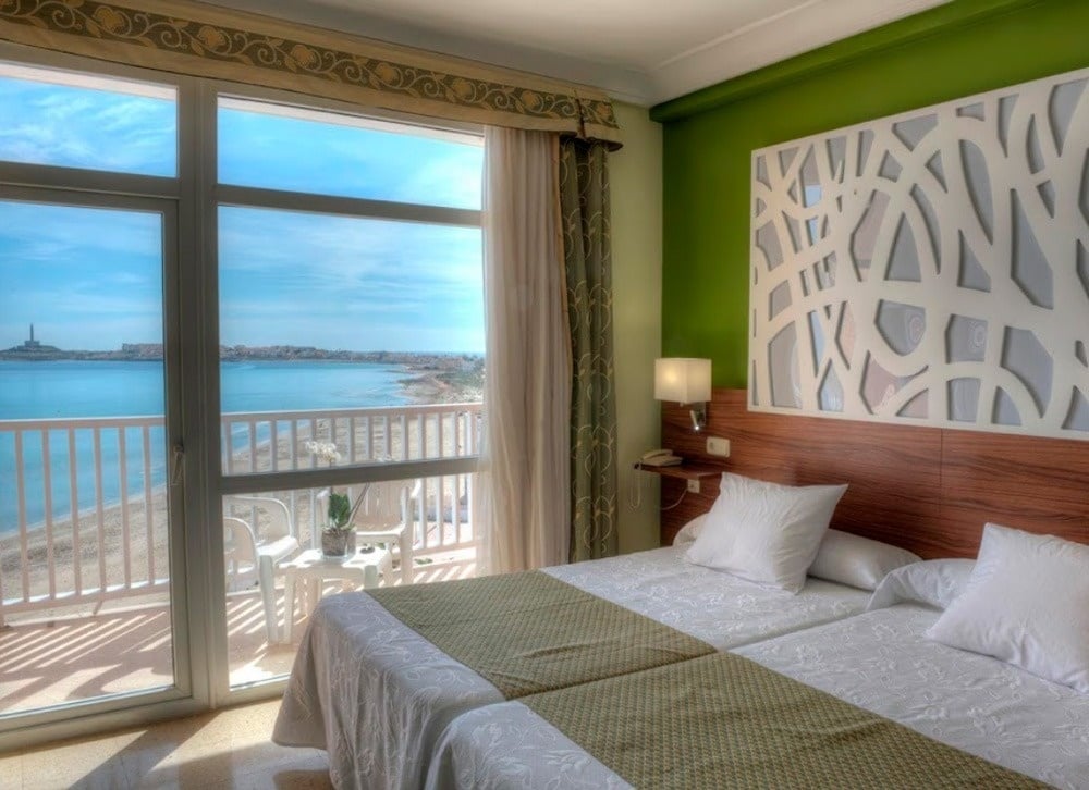 a hotel room with two beds and a view of the ocean