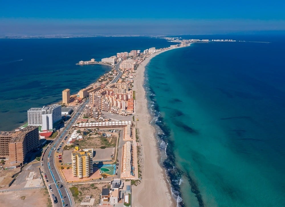 an aerial view of a beach with buildings in the distance