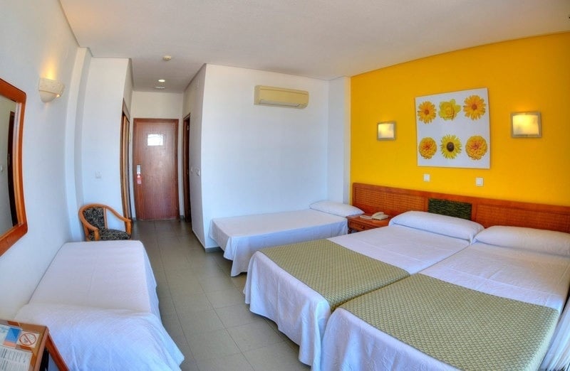 a hotel room with three beds and yellow walls