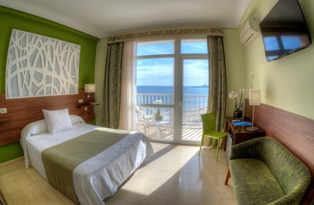 a hotel room with a bed and a balcony overlooking the ocean