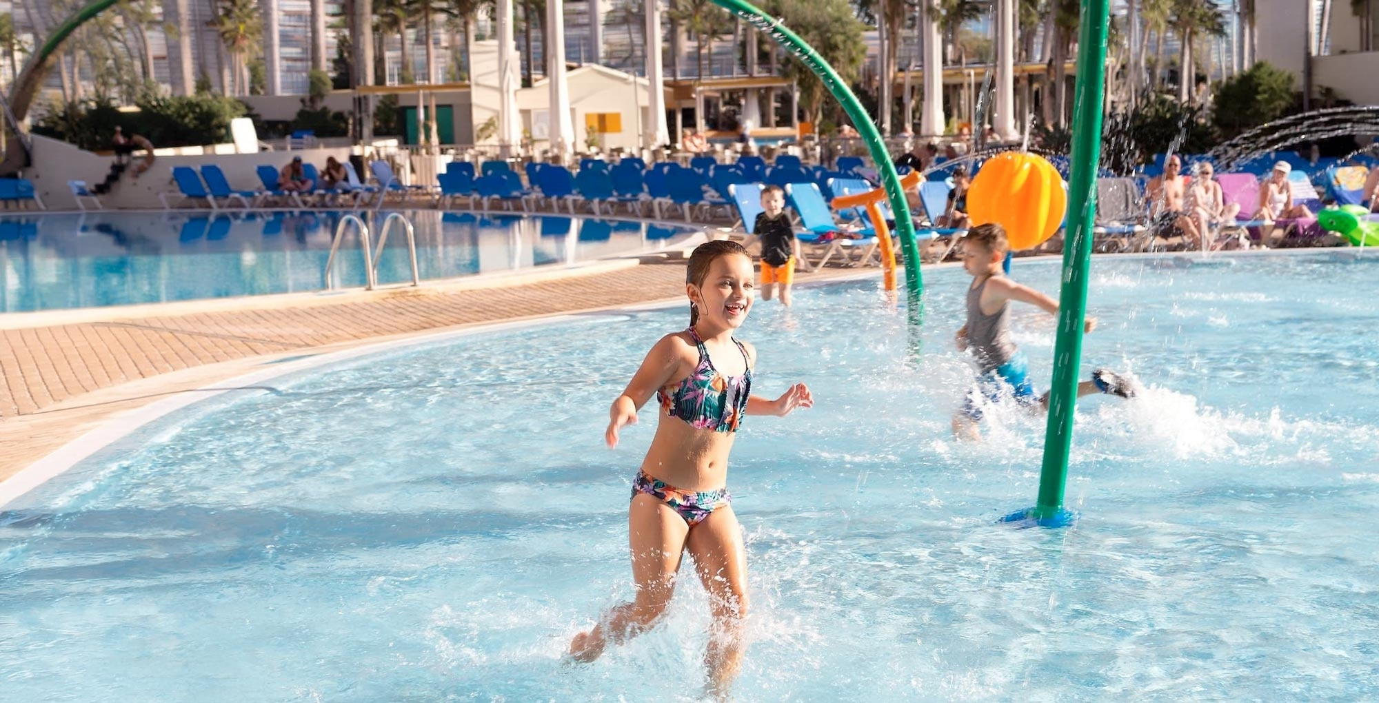 Niños divirtiéndose en la piscina con chorros de agua. 