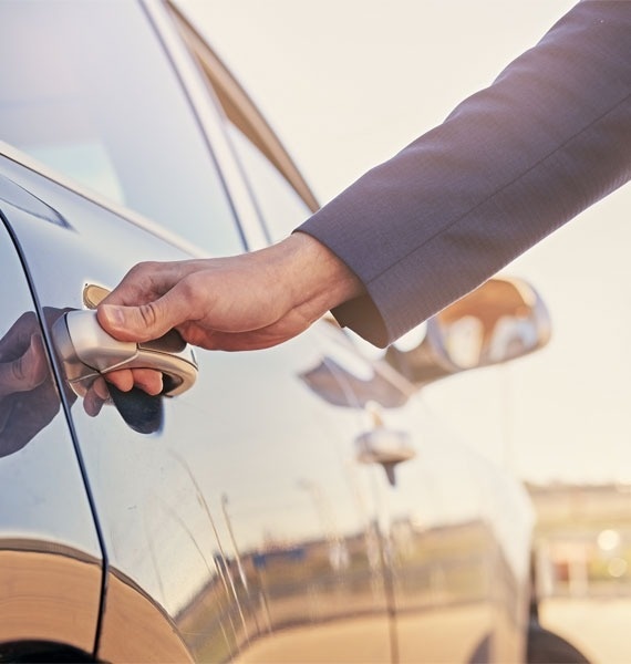 a man in a suit is opening the door of a car