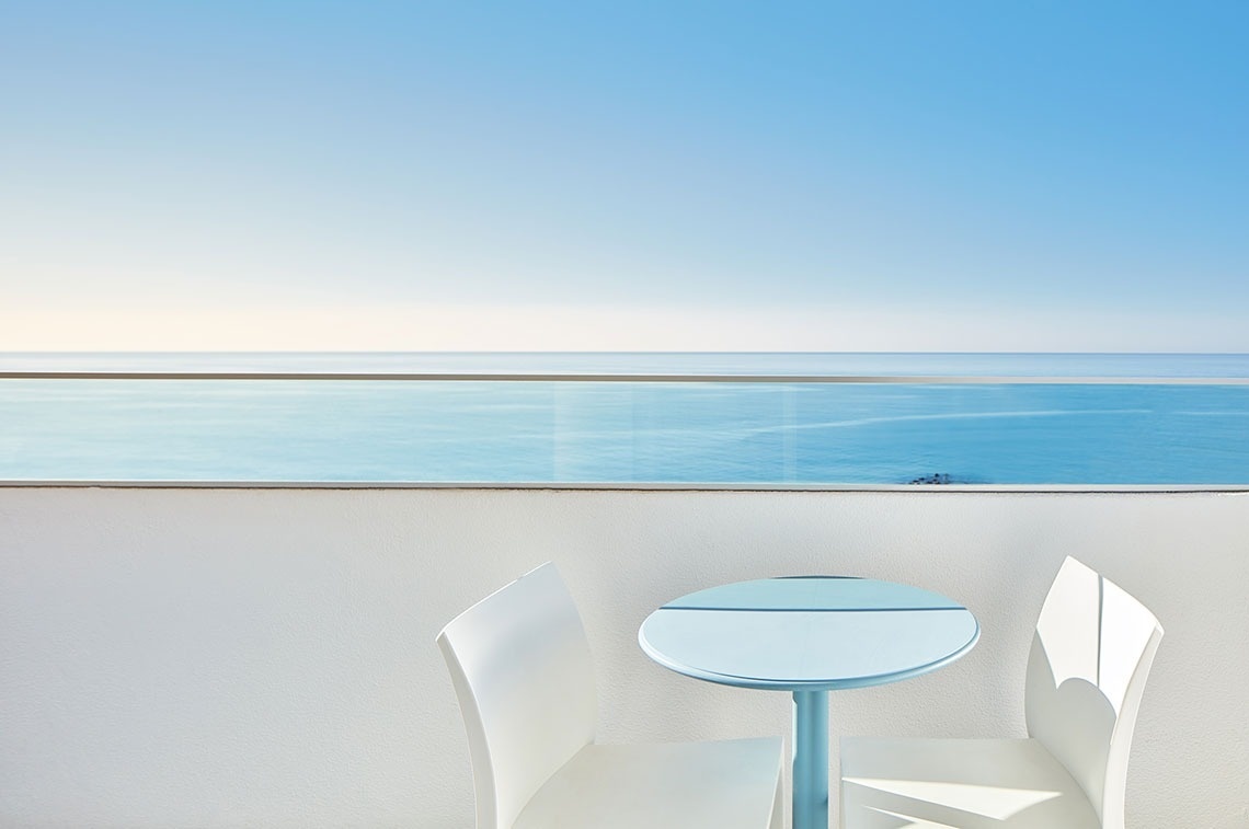 uma mesa e cadeiras em uma varanda com vista para o oceano