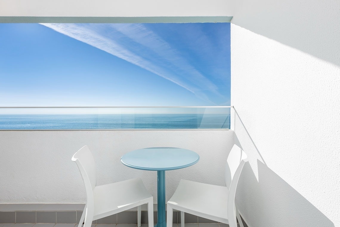 uma mesa e duas cadeiras em uma varanda com vista para o oceano