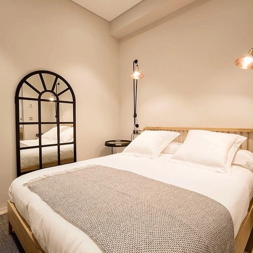 Dormitorio elegante con cama doble, espejo de arco negro y lámparas de pared, perfecto para tu estancia. U-Sense Granada Catedral