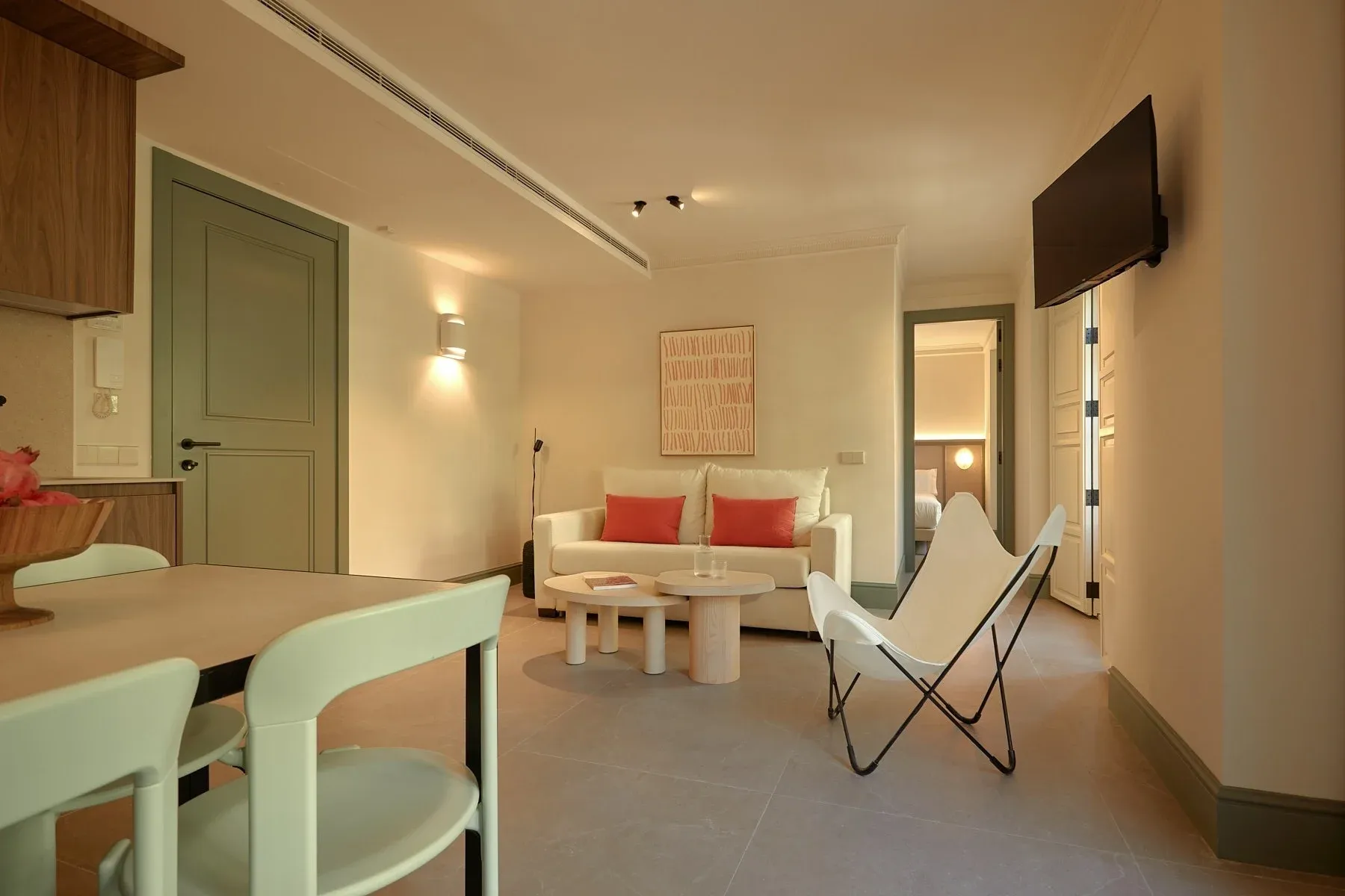 View of a modern open-plan apartment with an integrated living and dining room, featuring a beige sofa and a white butterfly chair. U-Sense