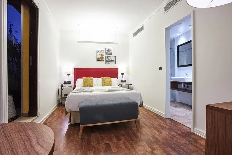 Cama confortable con cabecero rojo y mesitas de noche. U-Sense Sevilla Centro