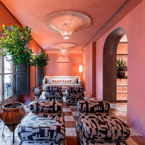 Sofás y tumbonas con estampado moderno en un salón de hotel rosa vibrante. U-Sense Granada Centro